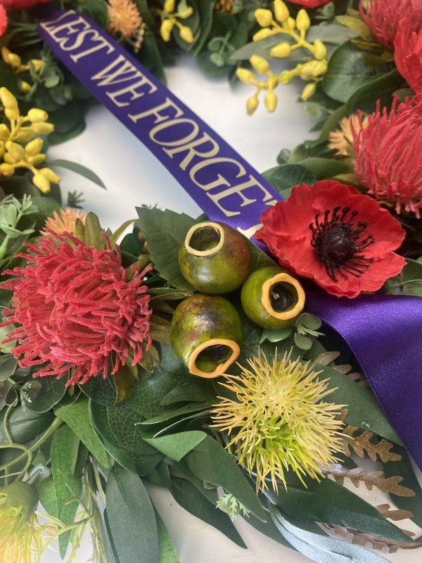 A zoomed in photo of a Remembrance Day Wreath featuring Gum Nuts, a Waratahs flower, a poppy, and a yellow native flower.