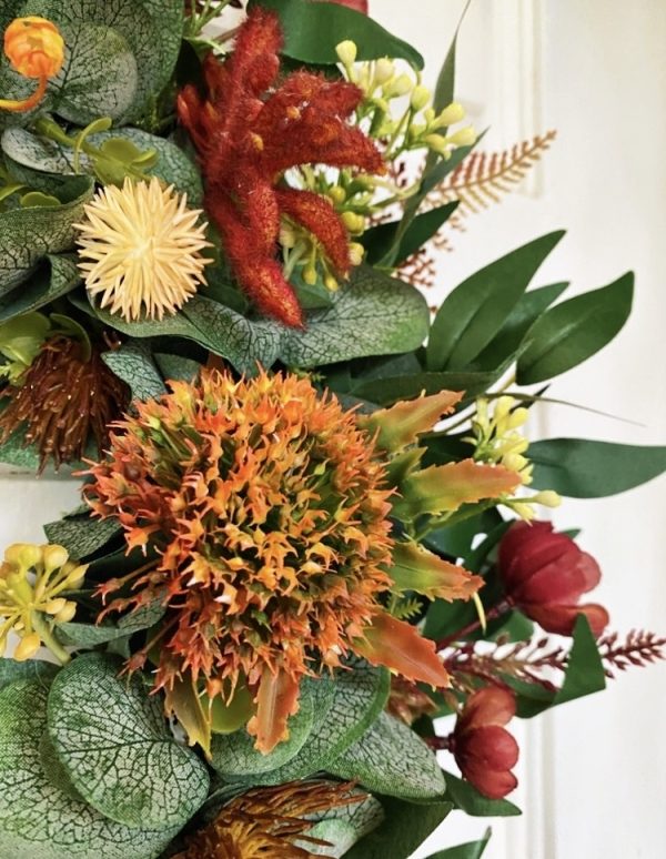 close up of native Christmas wreath showing orange native flower, yellow billy button and red kangaroo paw amongst green eucalyptus leaves